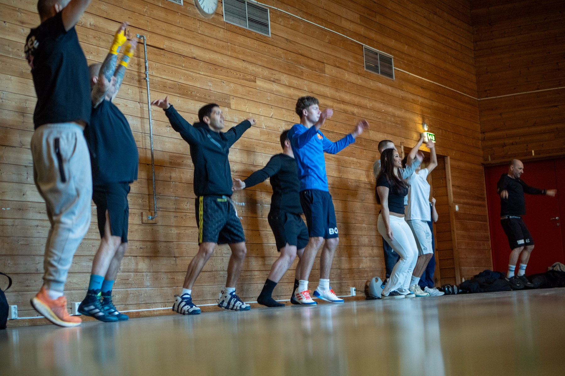 En gruppe deltakere varmer opp sammen i gymsalen